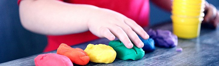 Die Hand eines Kindes, das mit Knetmasse spielt.