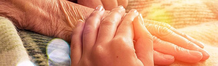 Person legt Hand auf die Hand einer anderen Person