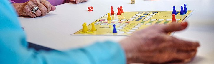 Zwei ältere Personen spielen Mensch-Ärgere-dich-nicht.