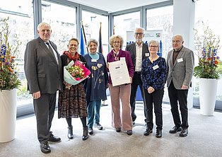 Sieben Personen stehen gemeinsam lächelnd.