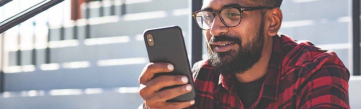 Junger Mann guckt auf sein Smartphone