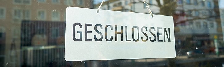 Schild mit Aufschrift "Geschlossen" hängt in einem Schaufenster.