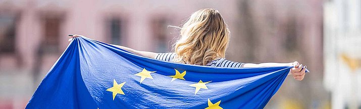 Person von hinten zu sehen, hält EU-Flagge