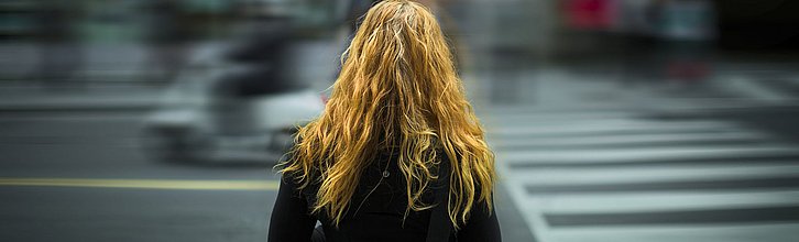 Frau von hinten zu sehen vor Zebrastreifen