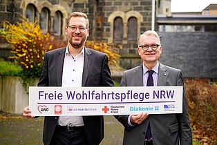 Christian Woltering übergibt den Vorsitz an Hartmut Krabs-Höhler symbolisch mit einem großen Schild.