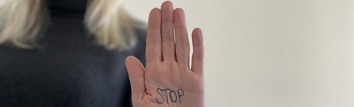Handfläche einer Frau im Fokus mit Aufschrift "Stop".