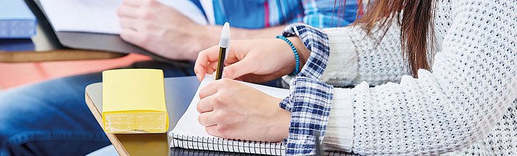 Hände, die etwas auf einen Block schreiben