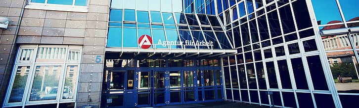 Verspiegelte Hausfassade mit Eingangsbereich eines Jobcenters.