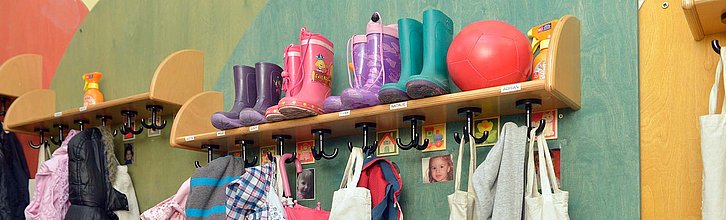 Garderobe in einer Kita mit vielen bunten Kleidungsstücken.