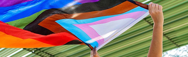 Hände halten eine Pride-Flag hoch