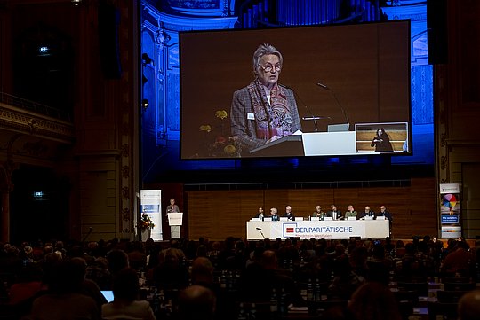 Blick auf das Podium der MV: groß auf der Leinwand Elke Schmidt-Sawatzki