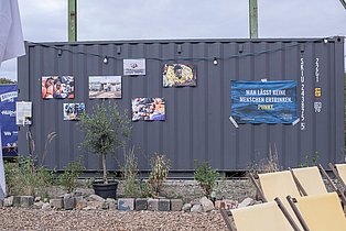 Ein grauer Schiffscontainer dient als Ausstellungsfläche für Fotosgrafien aus der Seenotrettung.