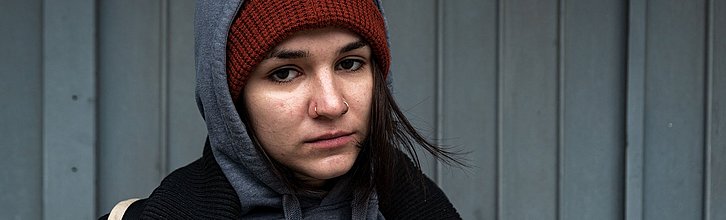 Junge, erwachsene Person guckt traurig in die Kamera.