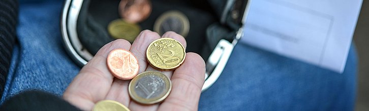 Einige wenige Münzen, die aus einer Geldbörse geholt werden