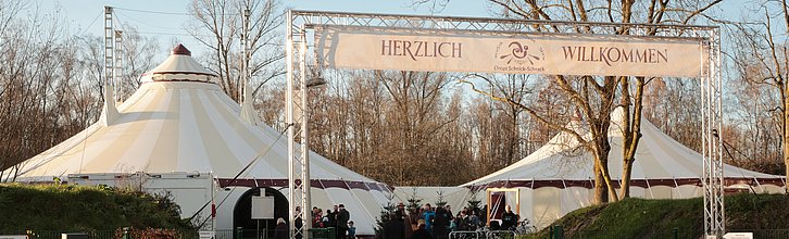 Zwei Zirkuszelter und Eingangsbanner mit Aufschrift "Herliche Willkommen"