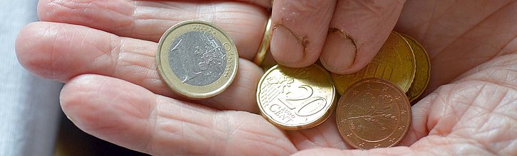 Auf einer faltigen Hand liegen Euro-Münzen.